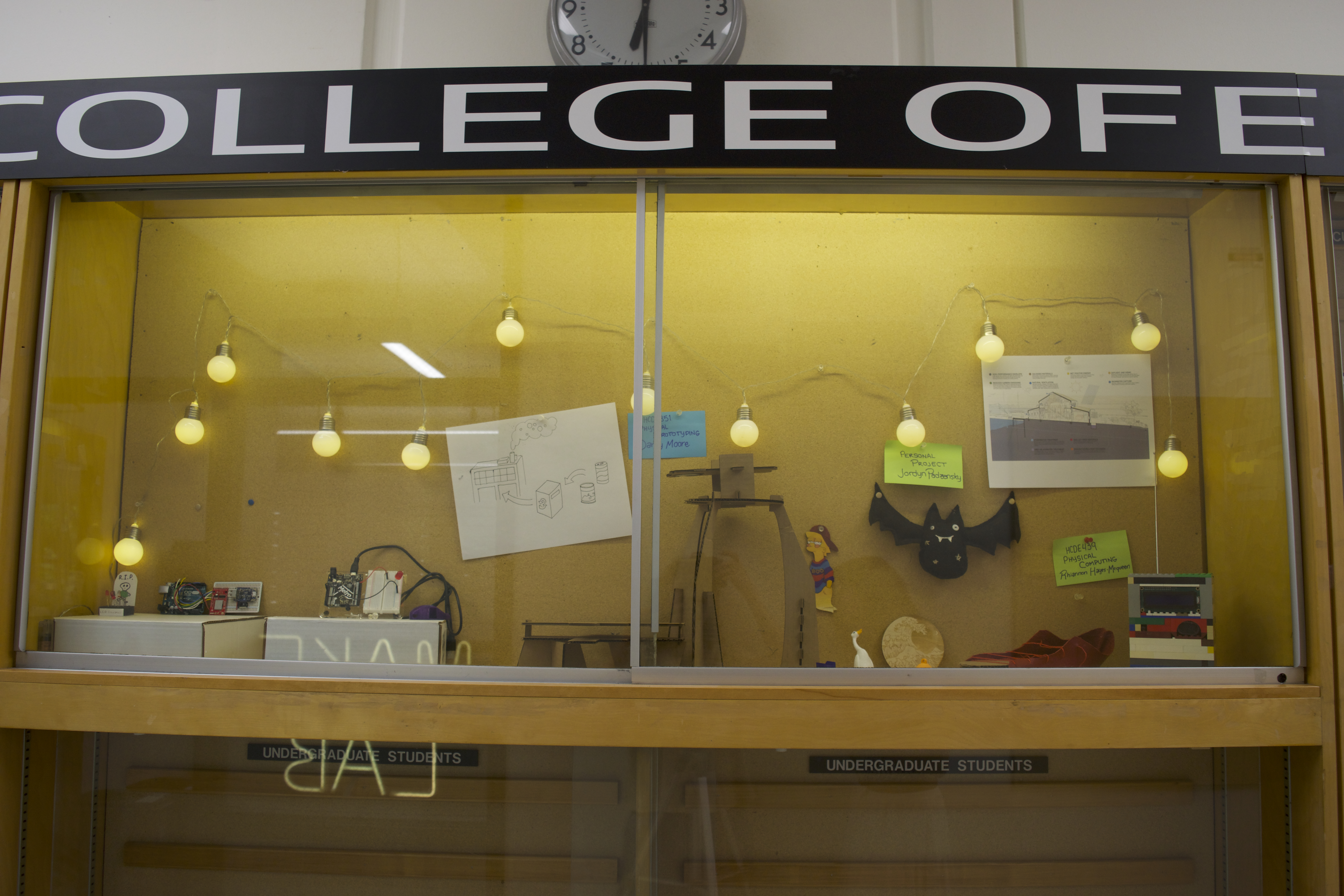 Trophy case in Sieg Hall displaying student projects — electronics, sketches, models, and MakeLab signage